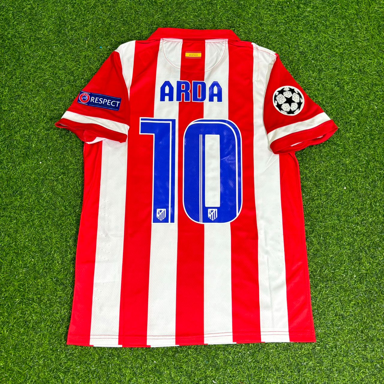 Red and white striped soccer jersey with number 10 and name 'Arda' on a green grass background