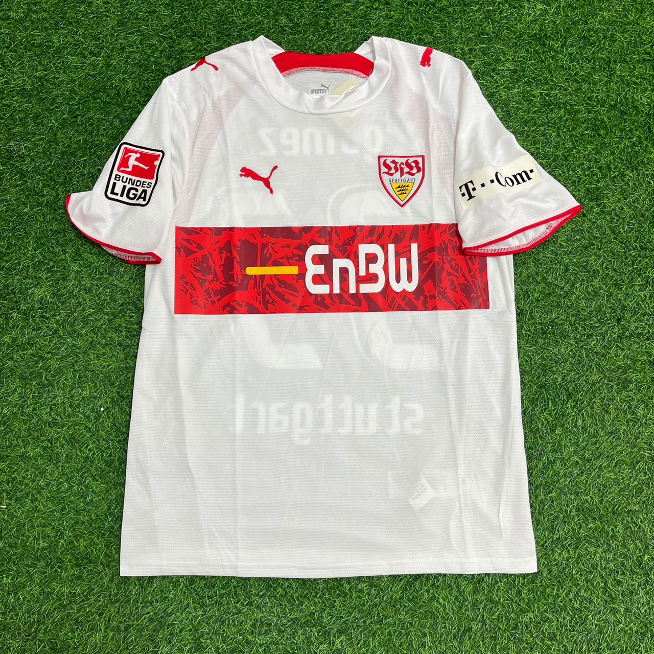 White sports jersey with red and black details on a green grass background